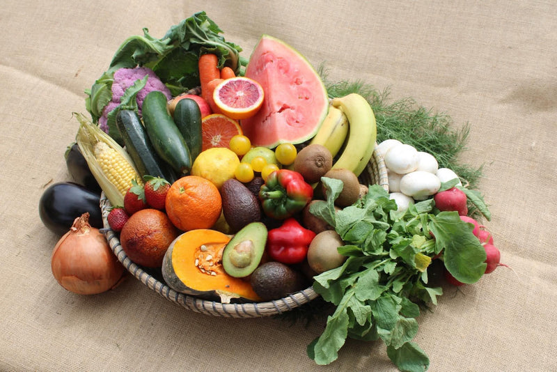 A woven basket filled with Organics Mattr seasonal mix of fruit and vegetables.