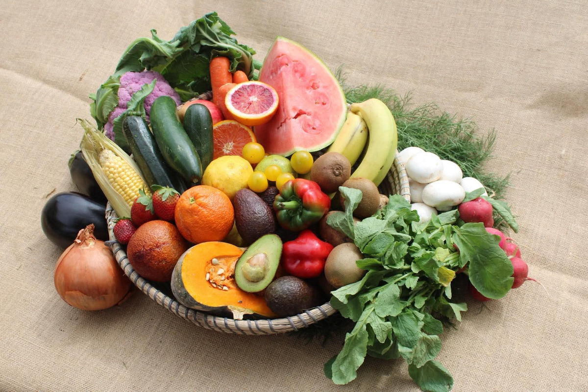 A woven basket filled with Organics Mattr seasonal mix of fruit and vegetables.